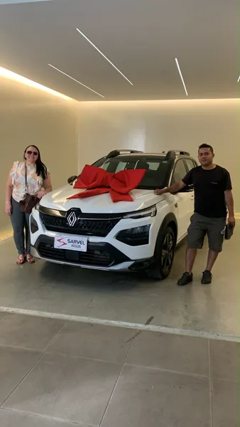 Cliente da Sarvel recebendo o carro, com o laço no capô