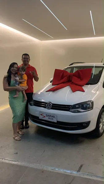 Cliente da Sarvel recebendo o carro, com o laço no capô