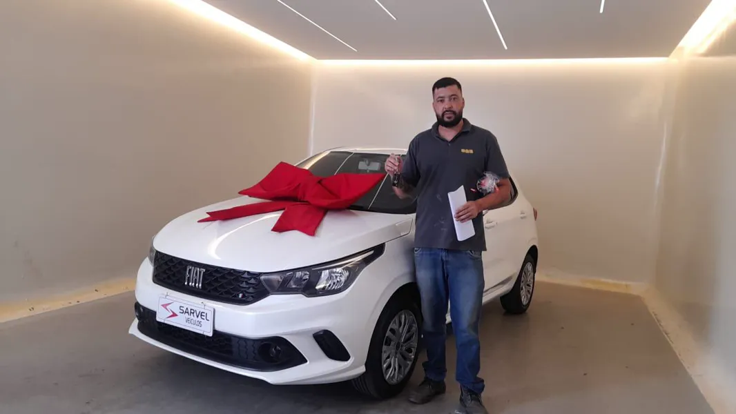 Cliente da Sarvel recebendo o carro, com o laço no capô