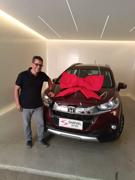 Cliente da Sarvel recebendo o carro, com o laço no capô