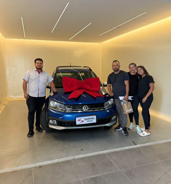 Cliente da Sarvel recebendo o carro, com o laço no capô