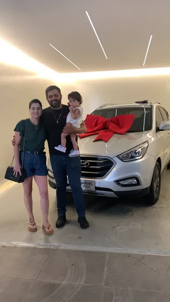 Cliente da Sarvel recebendo o carro, com o laço no capô