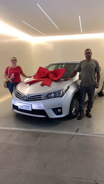 Cliente da Sarvel recebendo o carro, com o laço no capô