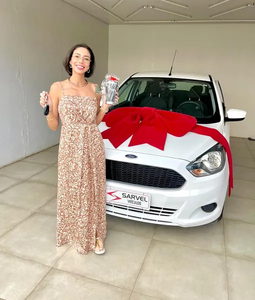 Cliente da Sarvel recebendo o carro, com o laço no capô