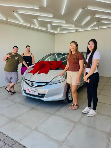 Cliente da Sarvel recebendo o carro, com o laço no capô