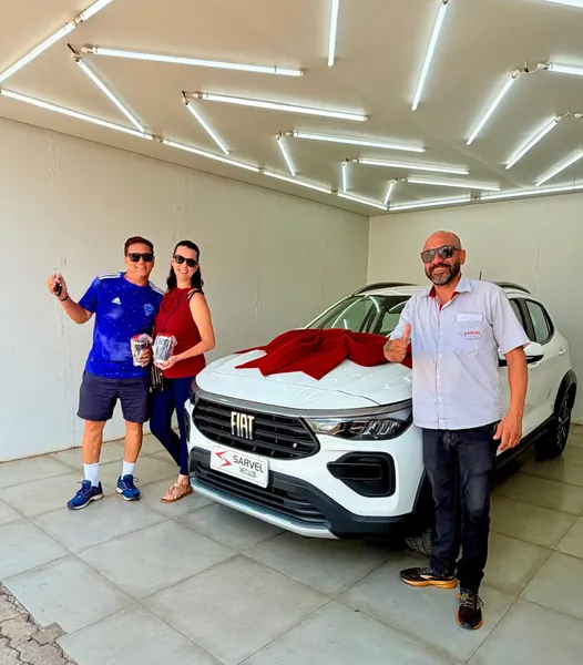 Cliente da Sarvel recebendo o carro, com o laço no capô