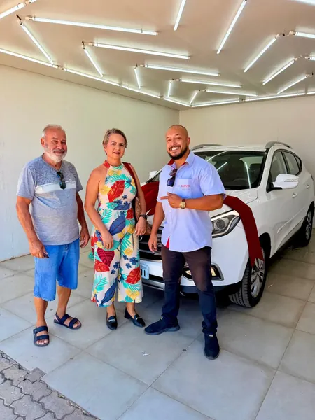 Cliente da Sarvel recebendo o carro, com o laço no capô