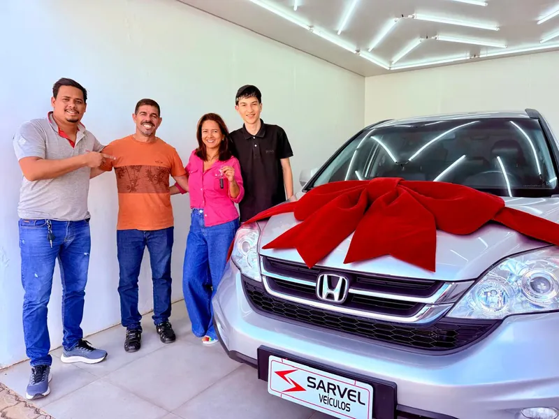 Cliente da Sarvel recebendo o carro, com o laço no capô